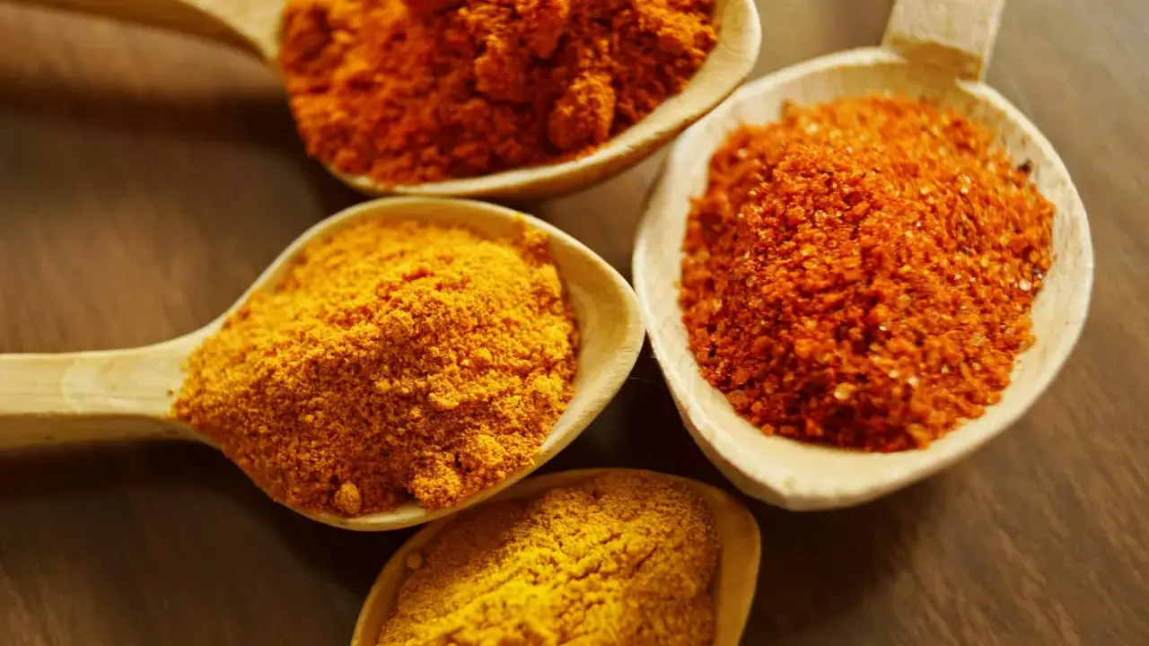 Cuillères en bois remplies d'épices colorées, dont le curcuma, parfait pour la peau.