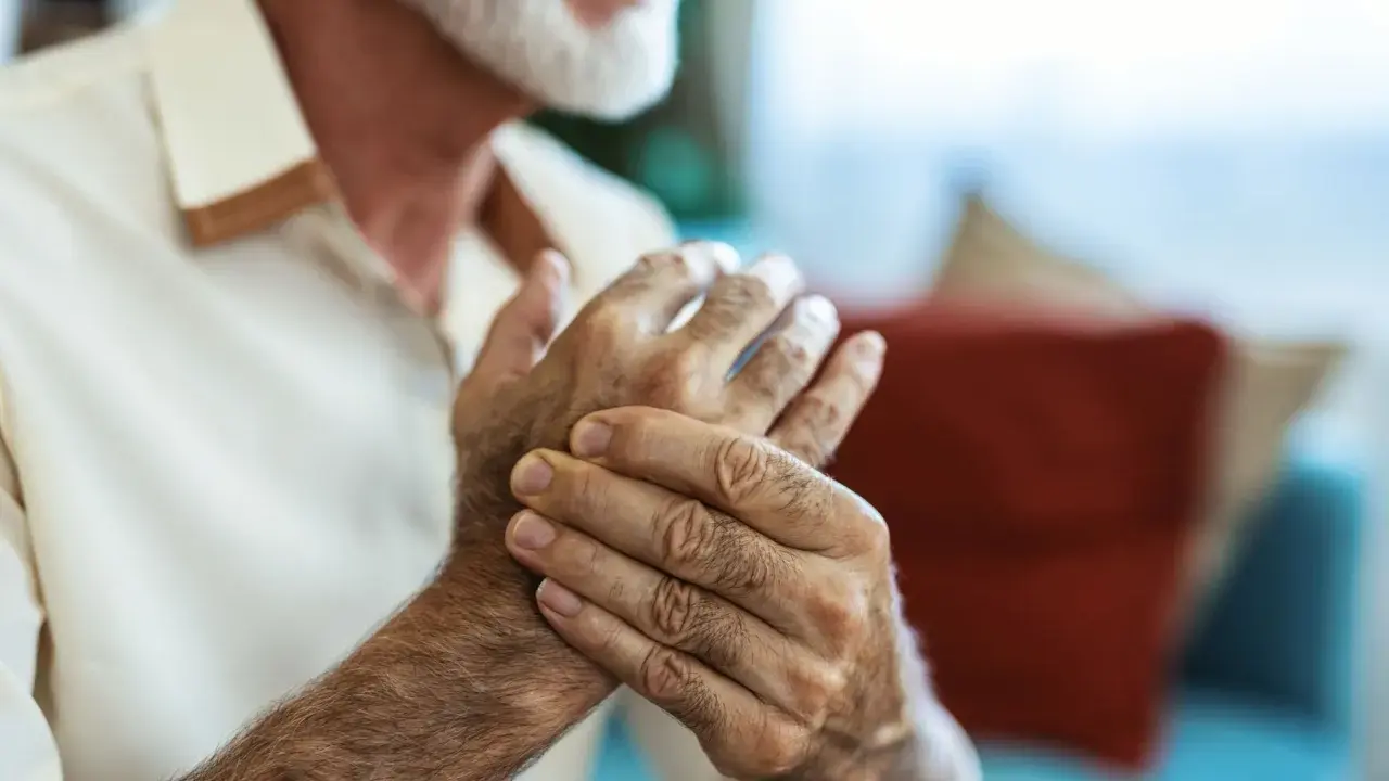 Homme âgé se tenant la main, cherchant un remède de grand-mère pour soigner crevasse doigt.