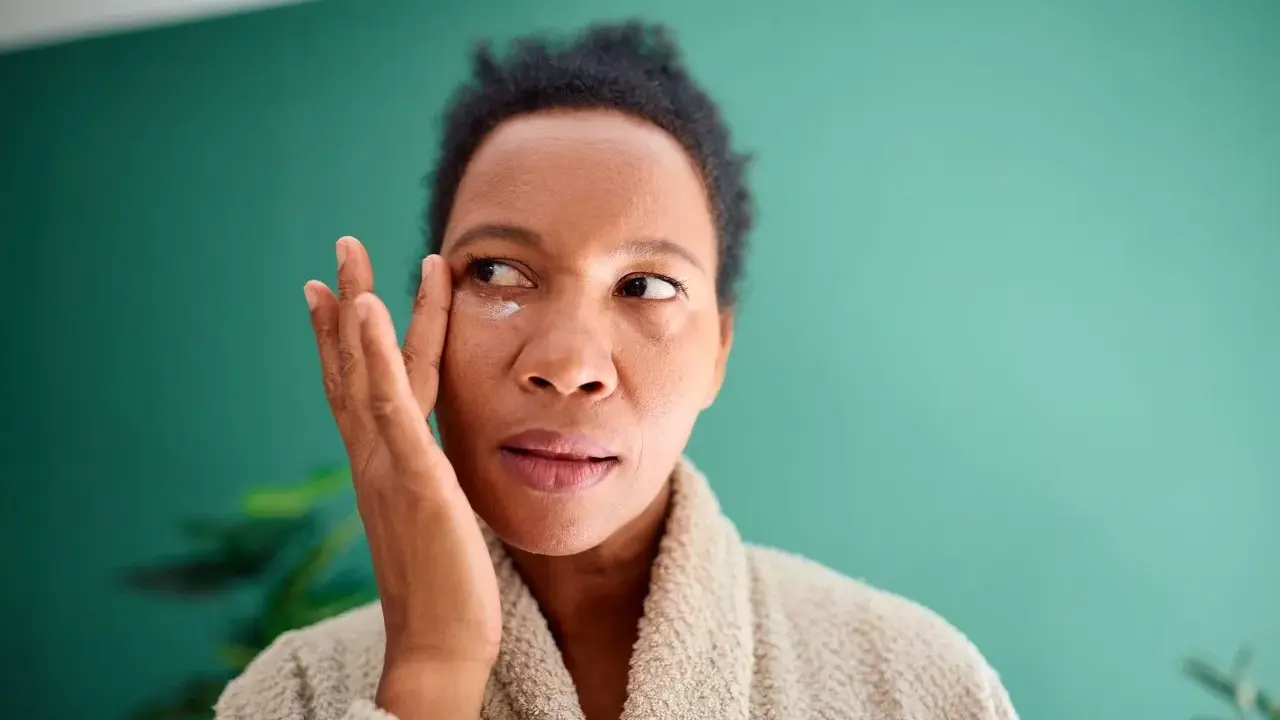 Femme appliquant une crème contour des yeux pour atténuer ses cernes vasculaires.