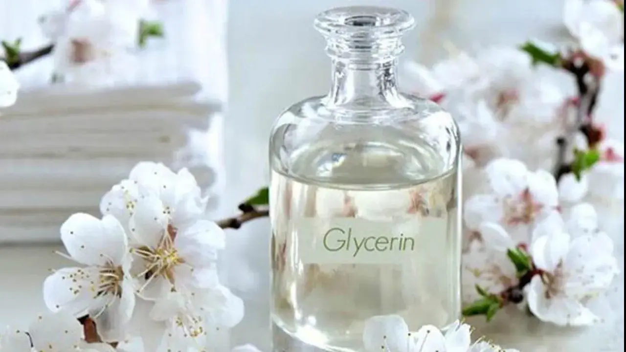 Bouteille de glycérine entourée de fleurs blanches. Attention, la glycérine peut présenter un danger si mal utilisée.