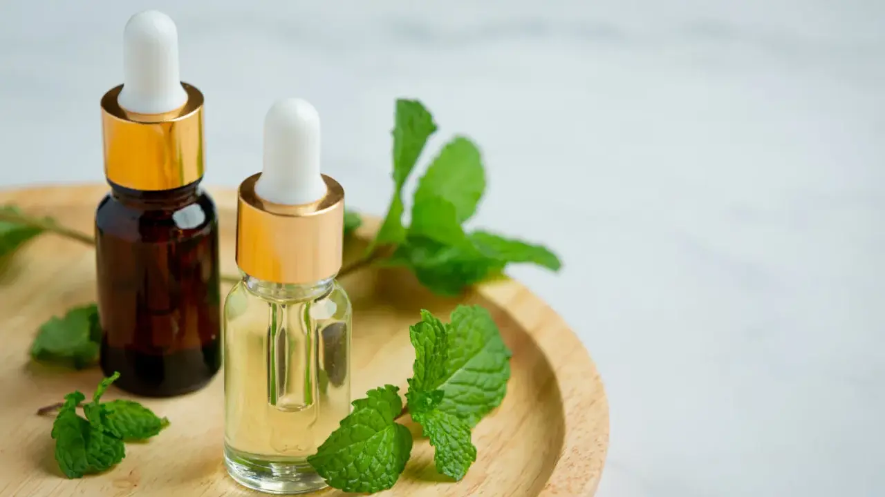 Deux flacons d'huile végétale, entourés de feuilles de menthe fraîche, suggèrent un remède naturel pour le psoriasis.