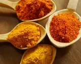 Cuillères en bois remplies d'épices colorées, dont le curcuma, parfait pour la peau.