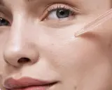 Une pipette dépose une goutte de sérum sur la joue d'une femme. Apprendre comment appliquer un sérum pour une peau éclatante.