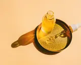 Flacon d'huile de tsubaki doré sur un plateau, avec une pipette prête à délivrer ses bienfaits.