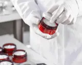 Mains gantées ouvrant un pot de crème cosmétique. Le polysorbate 60 est un ingrédient clé pour sa texture.