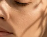 Gros plan sur une joue présentant une peau sèche et craquelée, accentuée par des ombres douces.