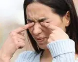 Une femme se frotte les yeux, une sensation de paupière qui gratte la dérange.