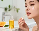 Une femme applique un sérum éclatant, riche en vitamine C et E, inspiré par la fraîcheur des oranges.