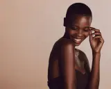 Une femme rit, sa peau foncée, riche en mélanine, le pigment responsable de la couleur de la peau, brille sous la lumière.
