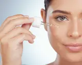 Une main applique une goutte de sérum sur le visage. Apprenez comment utiliser le rétinol pour une peau éclatante.