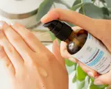 Application d'un sérum désaltérant à l'acide hyaluronique d'origine végétale sur la main. Le flacon pompe est tenu par une main aux ongles soignés.