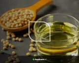 Grains de soja dans une cuillère en bois et un verre d'huile de soja, illustrant les huile de soja bienfaits pour la santé.