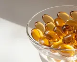 Gouttes dorées dans un bol en verre, évoquant l'huile de nigelle pour la grossesse et le bien-être.