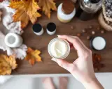 Maintenant, je ne veux plus mettre aucune crème sur ma peau. Une main tient un pot de crème, entouré de feuilles d'automne et de produits de soin.