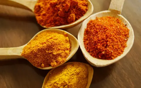 Cuillères en bois remplies d'épices colorées, dont le curcuma, parfait pour la peau.
