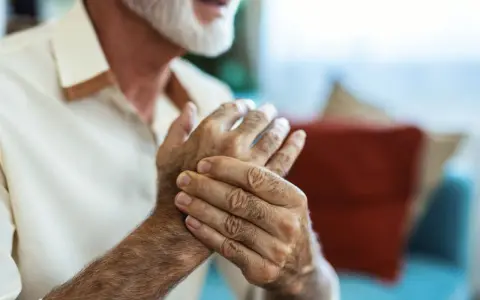 Homme âgé se tenant la main, cherchant un remède de grand-mère pour soigner crevasse doigt.