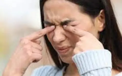 Une femme se frotte les yeux, une sensation de paupière qui gratte la dérange.