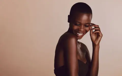 Une femme rit, sa peau foncée, riche en mélanine, le pigment responsable de la couleur de la peau, brille sous la lumière.
