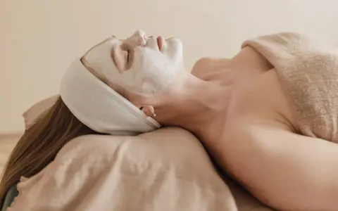 Visage couvert d'un masque blanc, une femme se détend. Attention à l'allantoïne, son danger potentiel pour la peau.