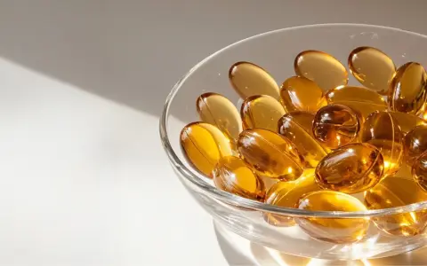 Gouttes dorées dans un bol en verre, évoquant l'huile de nigelle pour la grossesse et le bien-être.
