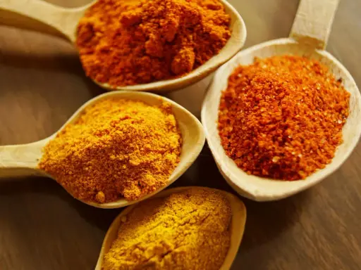 Cuillères en bois remplies d'épices colorées, dont le curcuma, parfait pour la peau.