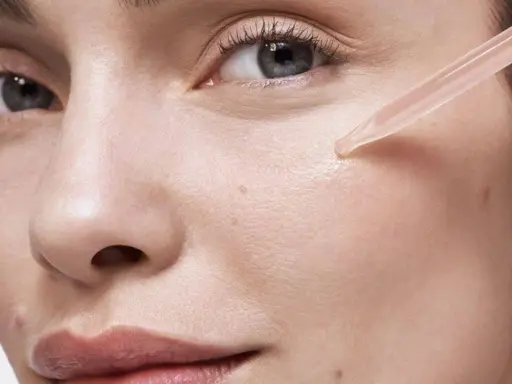Une pipette dépose une goutte de sérum sur la joue d'une femme. Apprendre comment appliquer un sérum pour une peau éclatante.