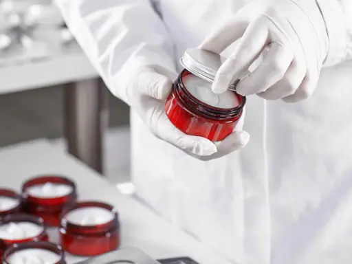 Mains gantées ouvrant un pot de crème cosmétique. Le polysorbate 60 est un ingrédient clé pour sa texture.