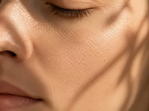 Gros plan sur une joue présentant une peau sèche et craquelée, accentuée par des ombres douces.