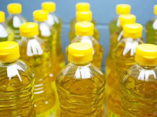 Plusieurs bouteilles d'huile de tournesol, au liquide doré, aux bouchons jaunes vifs. L'huile de tournesol, danger potentiel si mal stockée.
