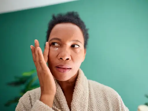 Femme appliquant une crème contour des yeux pour atténuer ses cernes vasculaires.