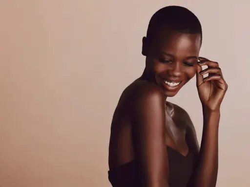 Une femme rit, sa peau foncée, riche en mélanine, le pigment responsable de la couleur de la peau, brille sous la lumière.