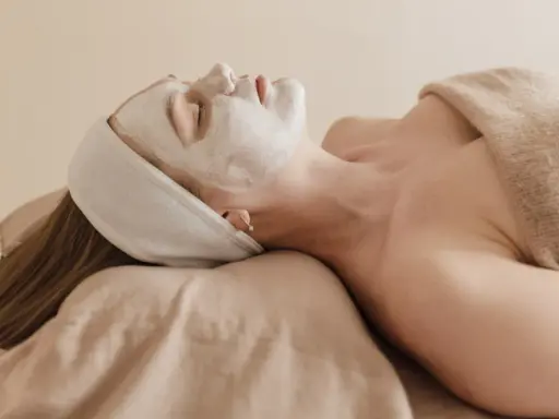 Visage couvert d'un masque blanc, une femme se détend. Attention à l'allantoïne, son danger potentiel pour la peau.