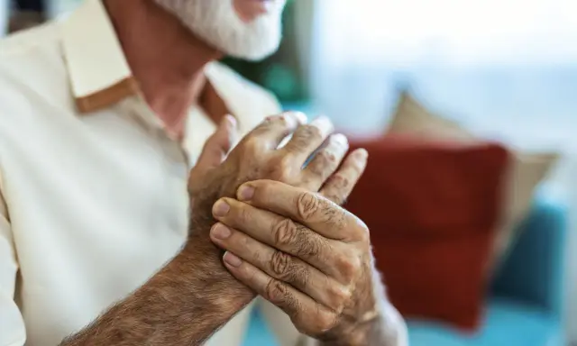 Homme âgé se tenant la main, cherchant un remède de grand-mère pour soigner crevasse doigt.