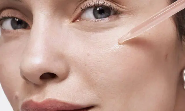 Une pipette dépose une goutte de sérum sur la joue d'une femme. Apprendre comment appliquer un sérum pour une peau éclatante.