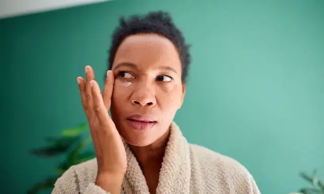 Femme appliquant une crème contour des yeux pour atténuer ses cernes vasculaires.