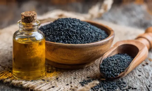 Flacon d'huile de nigelle à côté d'un bol de graines noires. L'huile de nigelle est réputée pour soulager l'eczéma.