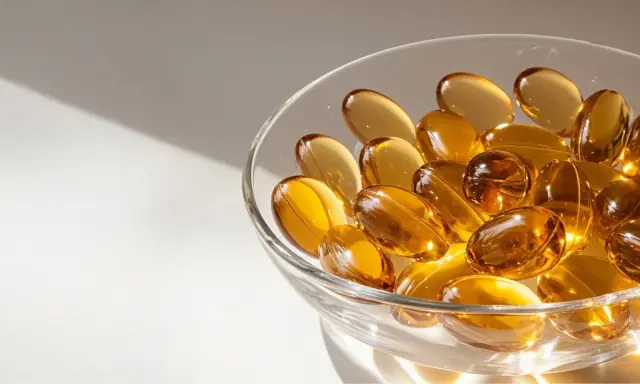 Gouttes dorées dans un bol en verre, évoquant l'huile de nigelle pour la grossesse et le bien-être.