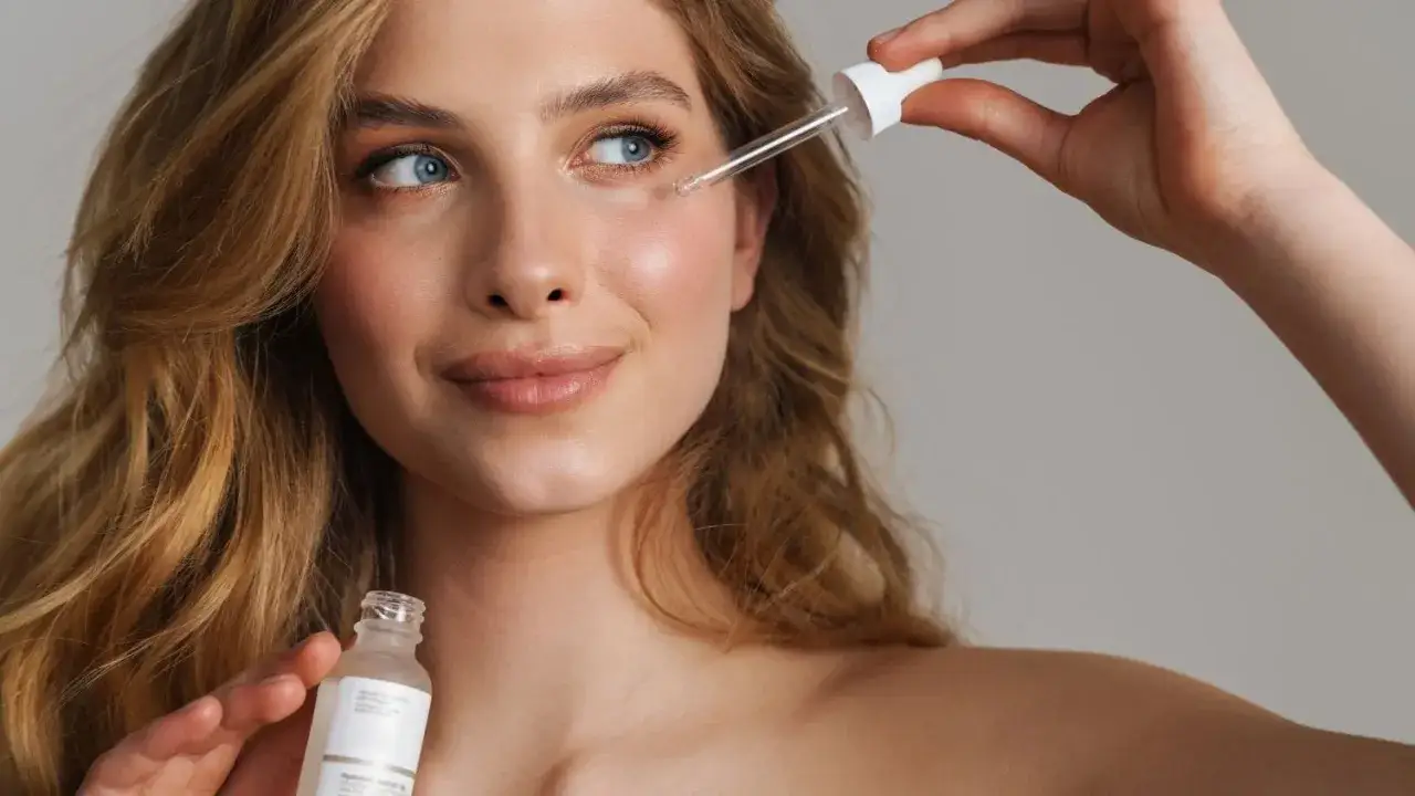 Une femme applique un sérum sur son visage avec une pipette. Découvrez comment appliquer un sérum pour une peau éclatante.