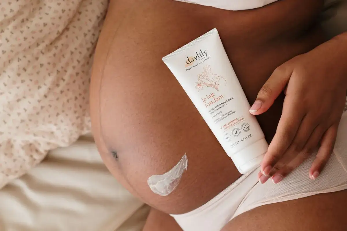 Ventre de femme enceinte avec une touche de cr&egrave;me. Le lait fondant Daylily aide &agrave; pr&eacute;venir la peau s&egrave;che pendant la grossesse.