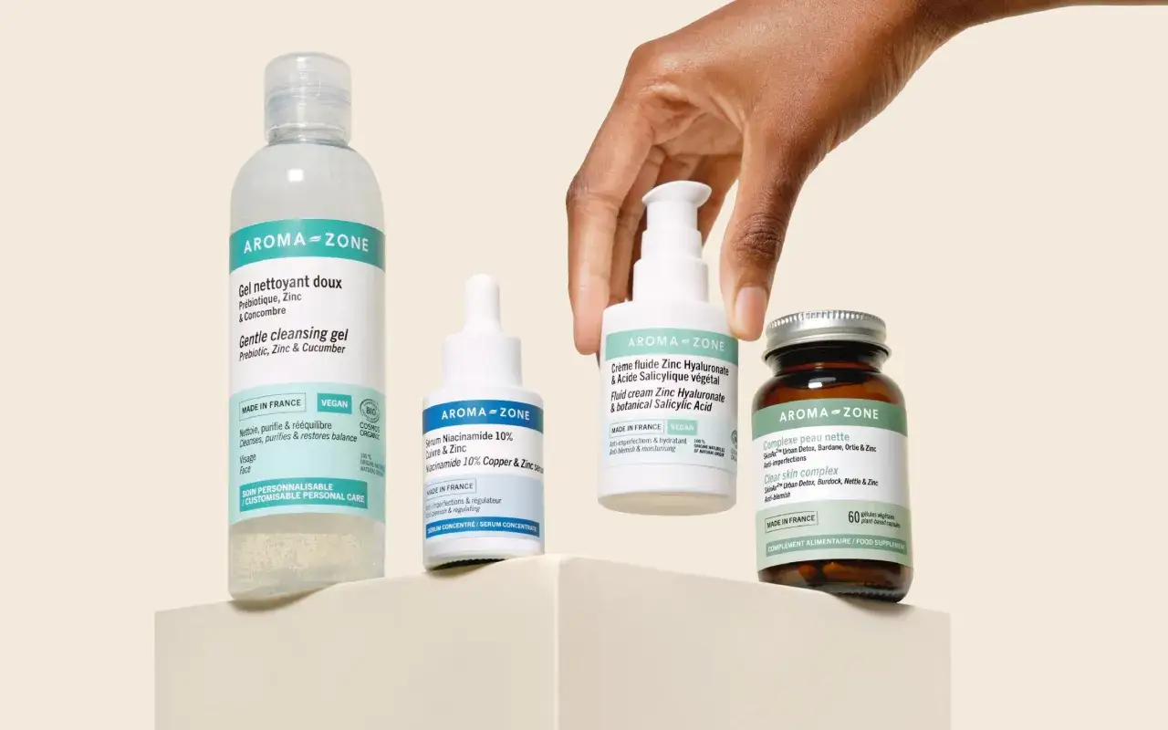 Main d'une personne saisissant une cr&egrave;me visage &agrave; l'acide salicylique v&eacute;g&eacute;tal, matin ou soir, aux c&ocirc;t&eacute;s d'autres produits Aroma-Zone.