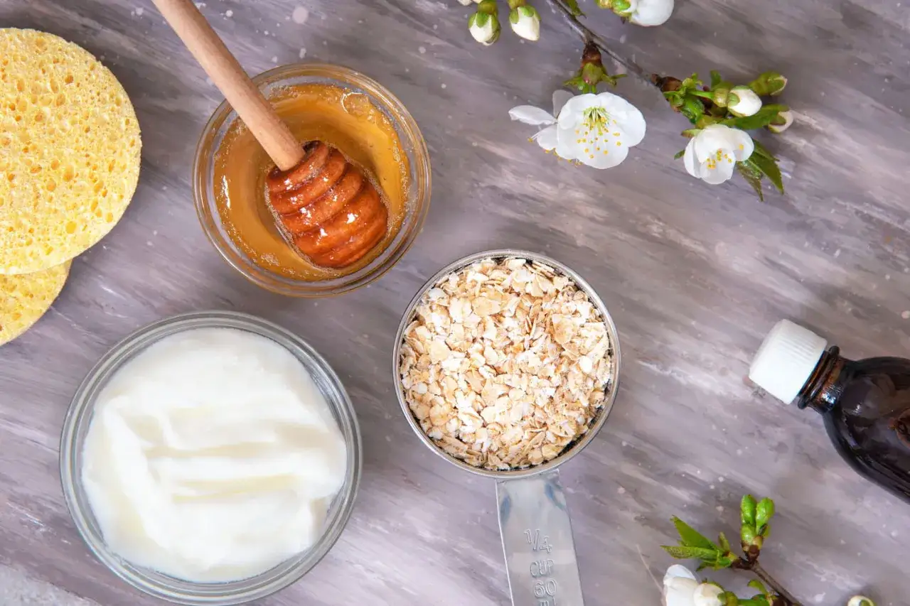 Ingrédients pour un eczéma traitement naturel : miel, avoine, yaourt, éponges et une fiole d'huile.