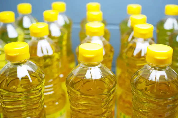 Plusieurs bouteilles d'huile de tournesol, au liquide doré, aux bouchons jaunes vifs. L'huile de tournesol, danger potentiel si mal stockée.